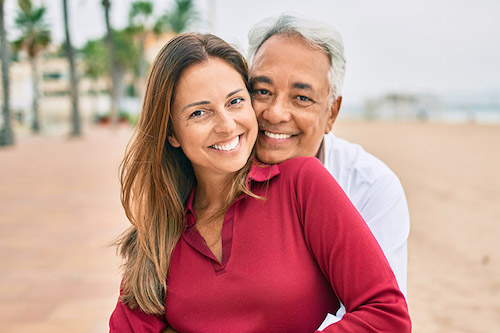 Image Text: 690x460-Middle age hispanic couple smiling happy and hugging sitting on the bench.